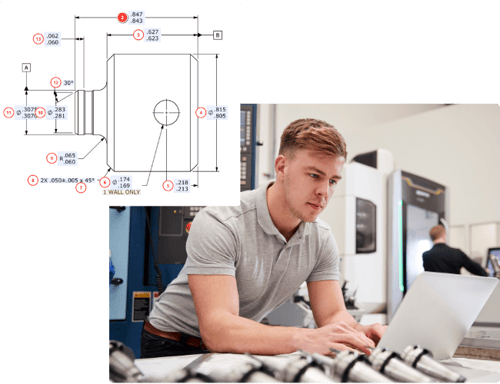 Engineer reviews technical drawing next to a CNC 5-axis mill