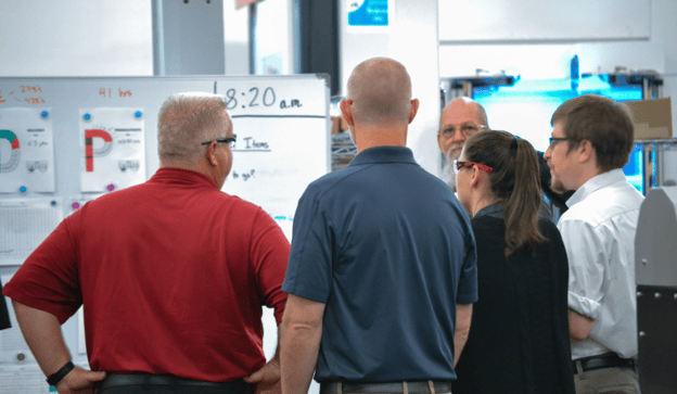 Managers huddle on production floor during daily Gemba walk