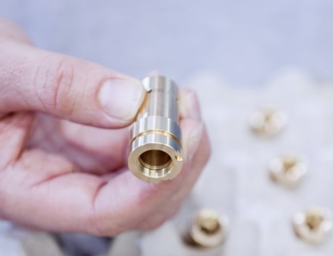Machinist visually inspects a machined brass component