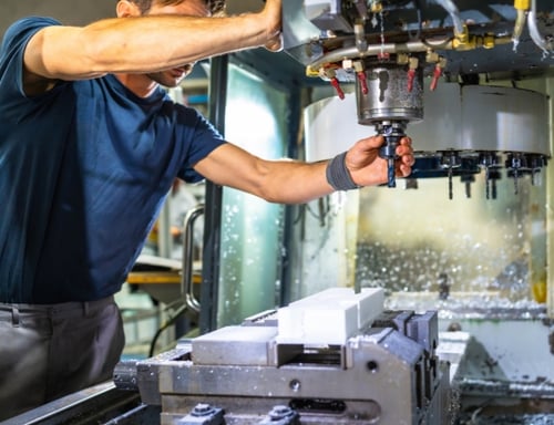 A machinist manually loads a cutting tool into a 3-axis end mill