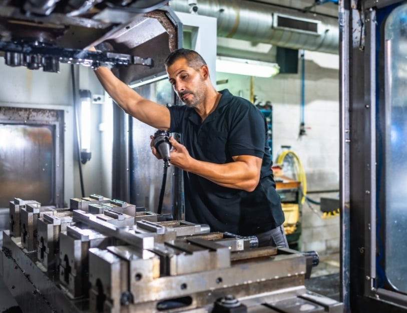 Machinist visually inspects an endmill while setting up a 3-axis mill