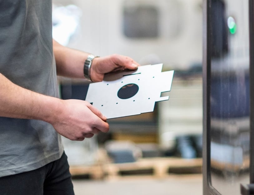 An engineer visually inspects a sheet metal part's flatness