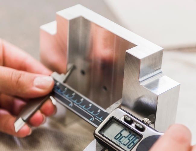 Machinist inspects Inconel part with calipers