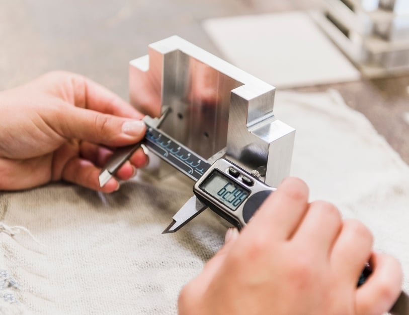 Machinist manually inspects a part with calipers